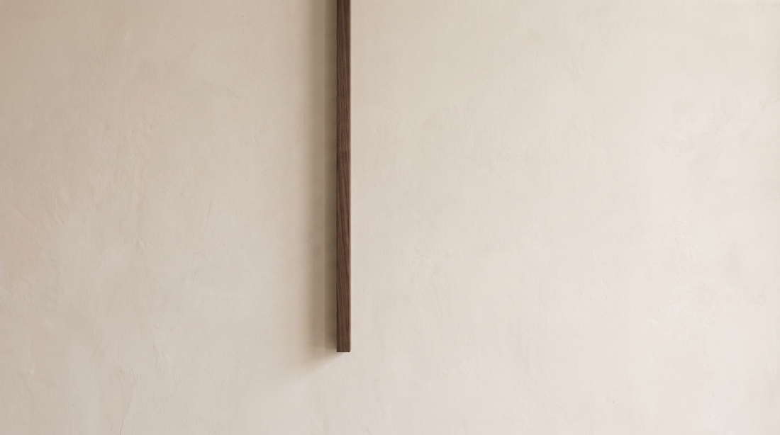 Abstract composition with one tidy dark line descending against soft plaster