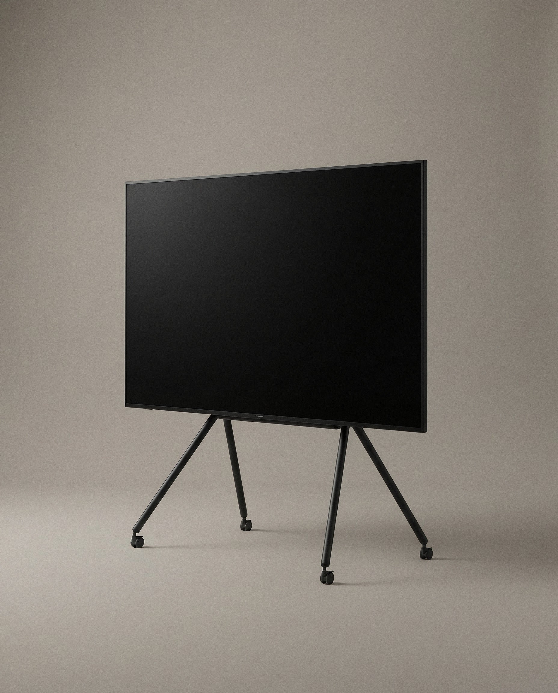 Black Studio TV Stand seen from the front, showing the splayed leg geometry and casters